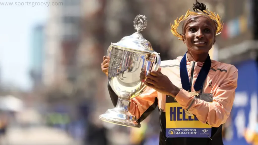 Hellen Obiri, of Kenya, raises her arms as she crosses the finish line to win the women's division of the Boston Marathon.