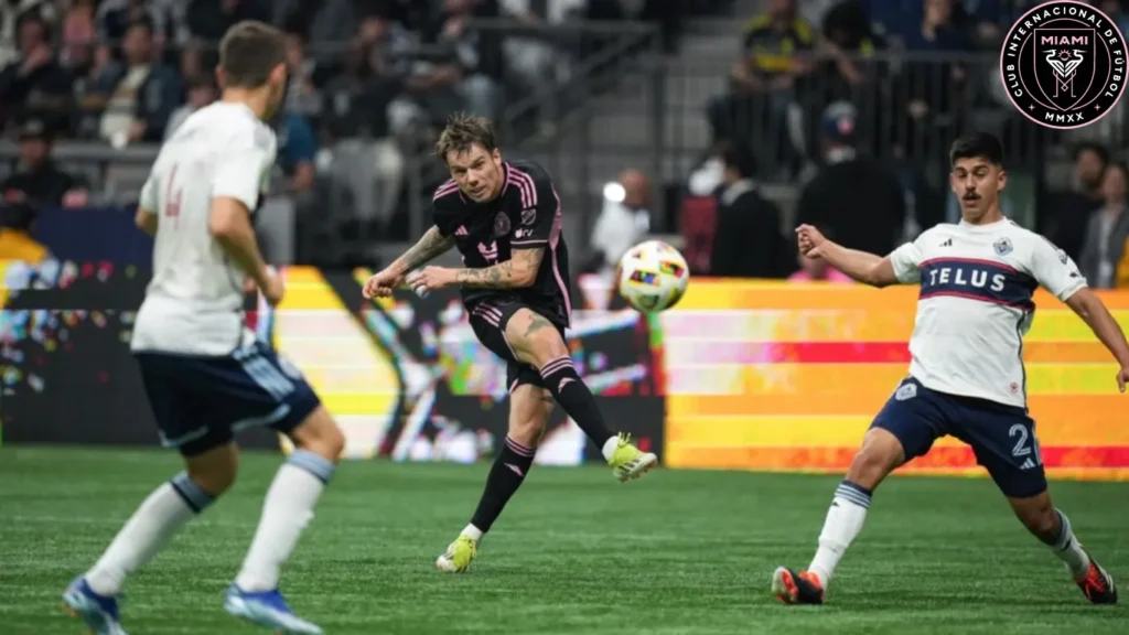 During the first half of an MLS soccer match in Vancouver on Saturday, May 25, 2024, Inter Miami's Robert Taylor, positioned at the back center, successfully scores a goal by striking the ball past Vancouver Whitecaps' Mathias Laborda, positioned at the front right, and Ranko Veselinovic, positioned at the front left.