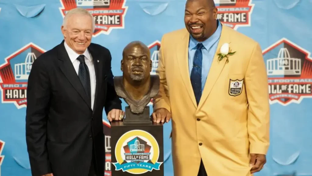 Jerry Jones and Larry Allen are captured in a poignant moment as they pose together with Allen's bust during the Pro Football Hall of Fame 2013 Enshrinement Ceremony at Fawcett Stadium in Canton, Ohio, on Saturday, August 3, 2013. It's a touching scene marking Allen's induction into the esteemed Hall of Fame, celebrating his outstanding contributions to the game of football.